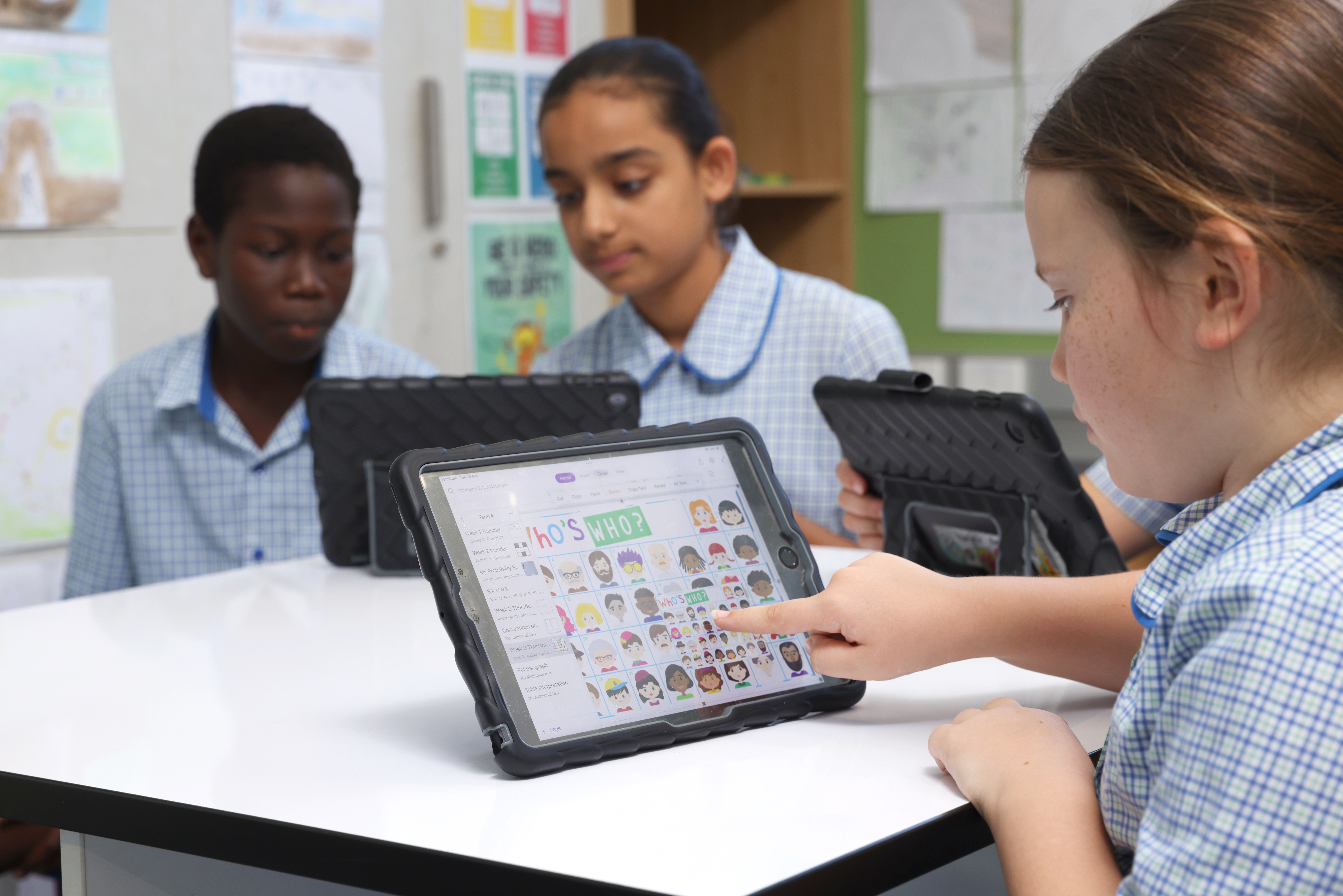 Students sitting at a desk using iPads